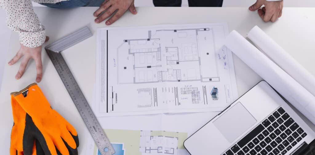 a person's hand on a table with a blueprint