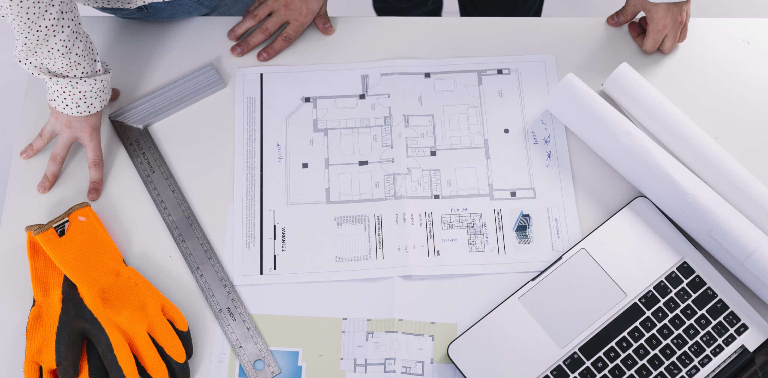 a person's hand on a table with a blueprint